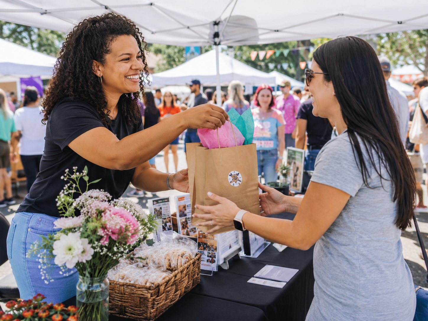 A local vendor sharing a curated gift bag with an attendee at a community festival